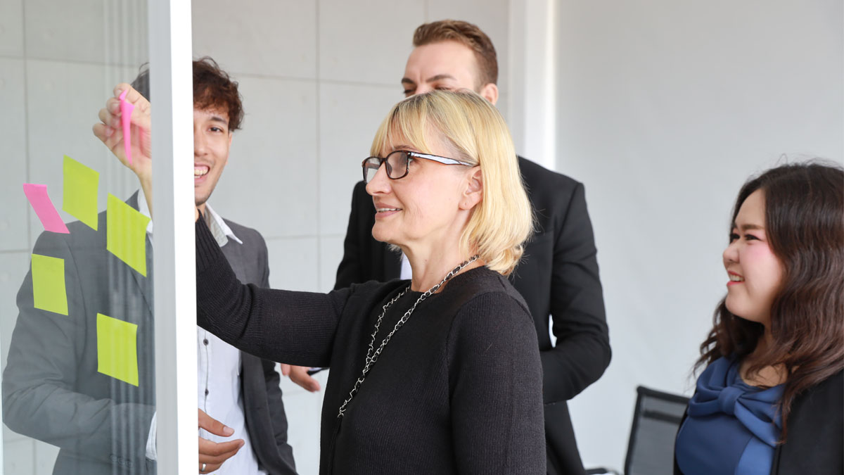 People working on a see-through board using post it notes