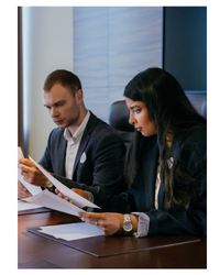 Photo of a man and a woman in suits reading official papers.