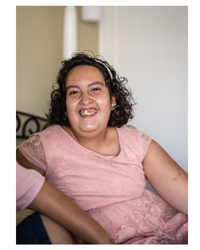 A girl with intellectual disability wearing a pink top and smiling.