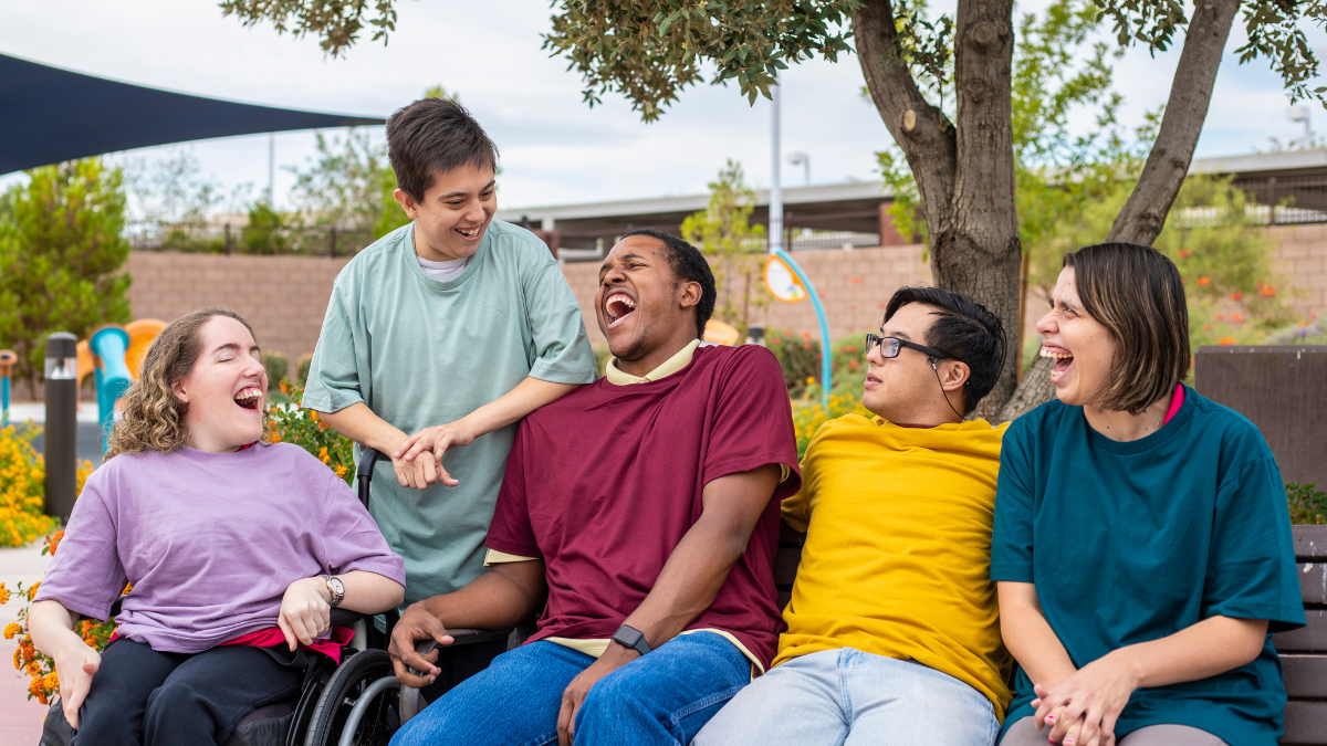A group of five people with intellectual disability laughing together.
