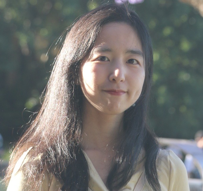 A photo of Peiwen Lao. She is outside. She is looking at the camera and smiling. You can only see her head and shoulders in the photo.