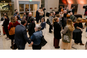 Photo of a group of people standing around talking in groups.