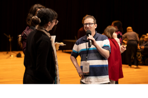 Photo of Ricky Kremer from the Centre holding a microphone and talking to people.
