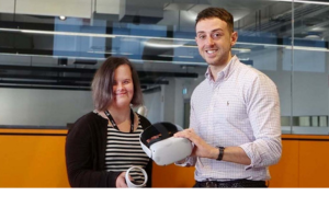 Photo of two researchers. One has intellectual disability. They are holding parts of a virtual reality headset.