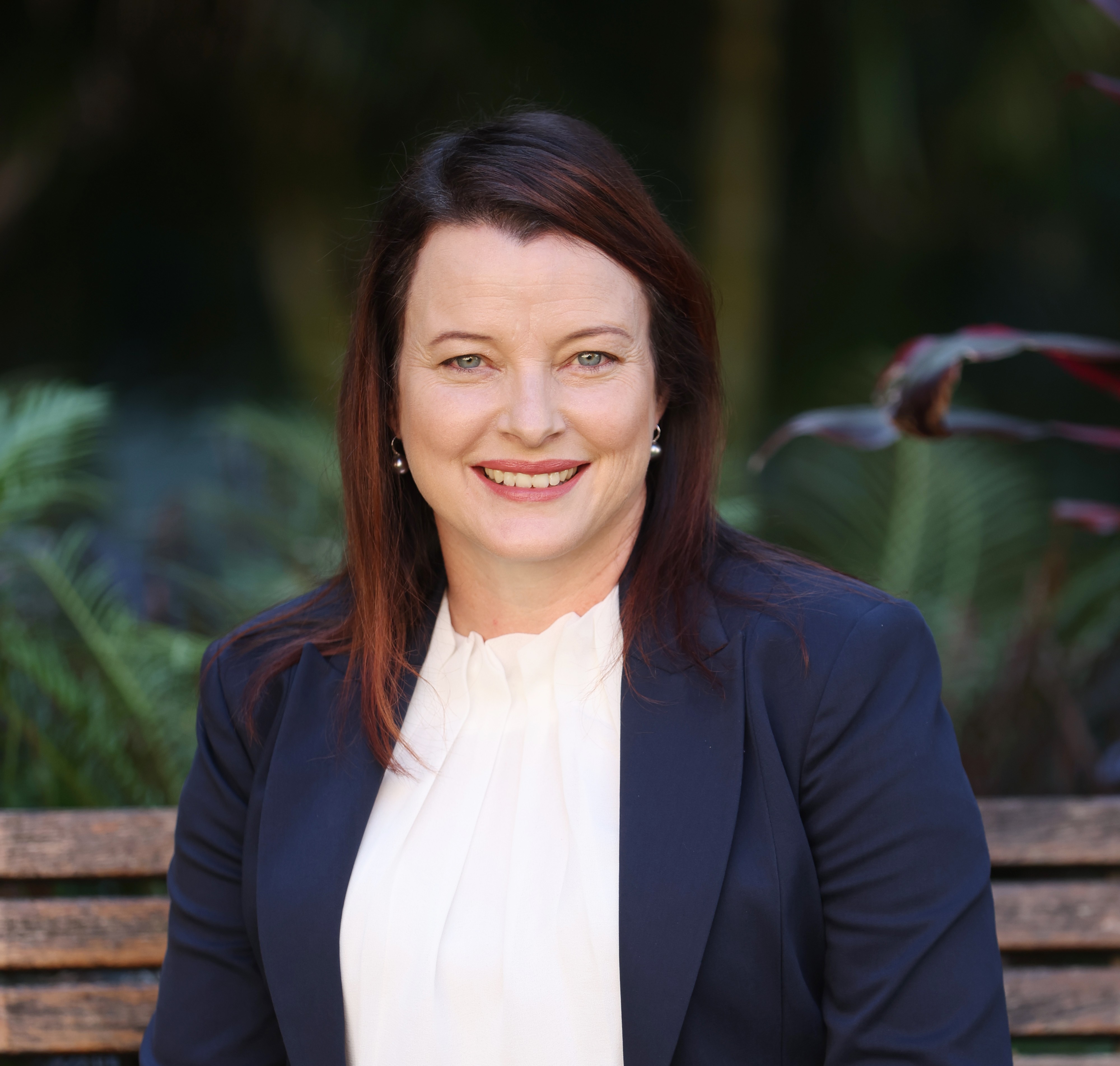 A photo of Cathy Franklin. She has long brown hair. She is wearing a navy blue blazer and a white blouse. She is smiling at the camera.