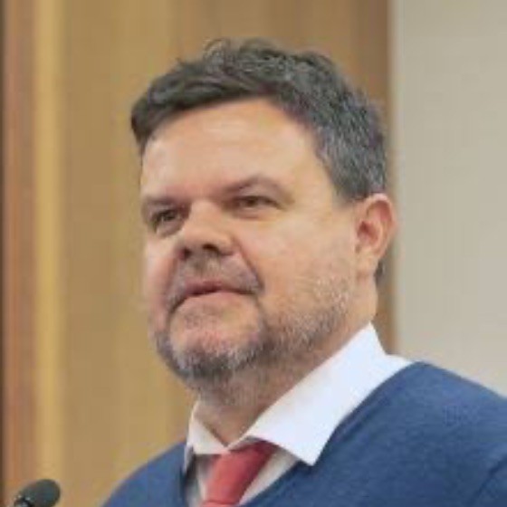 A photo of Damian Griffis. He is wearing a white collar shirt, a red tie, and a blue suit jacket.