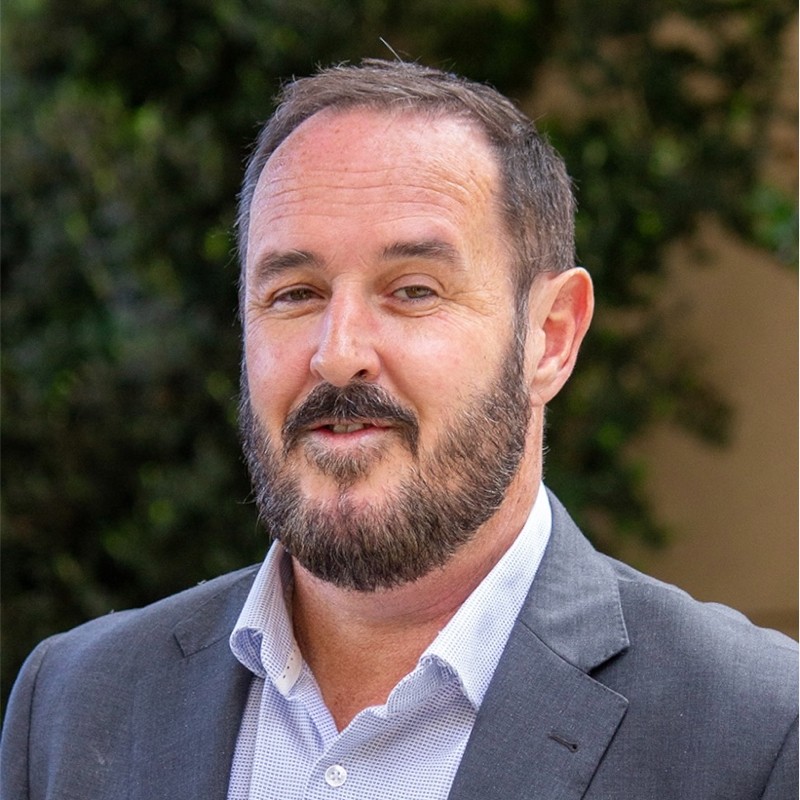 A photo of Heath Dickens. He is wearing a grey suit.