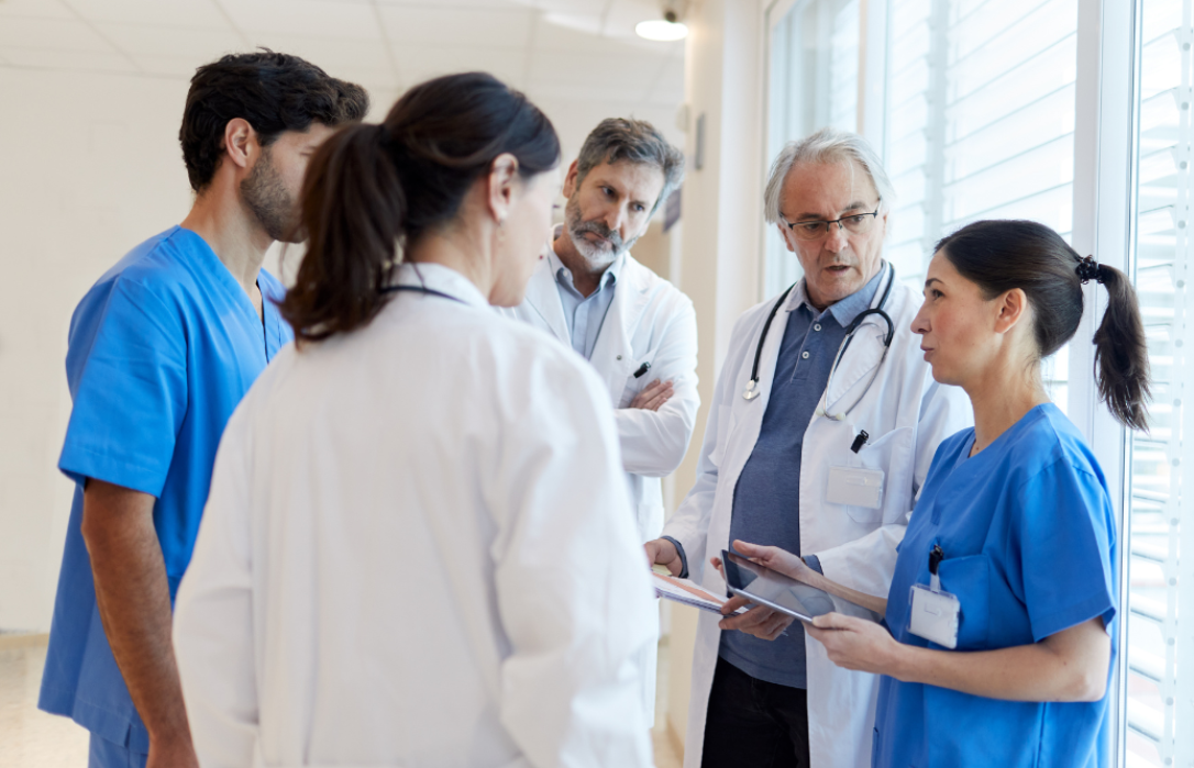 Photo of a group of healthcare professionals standing in a hospital and talking to each other.