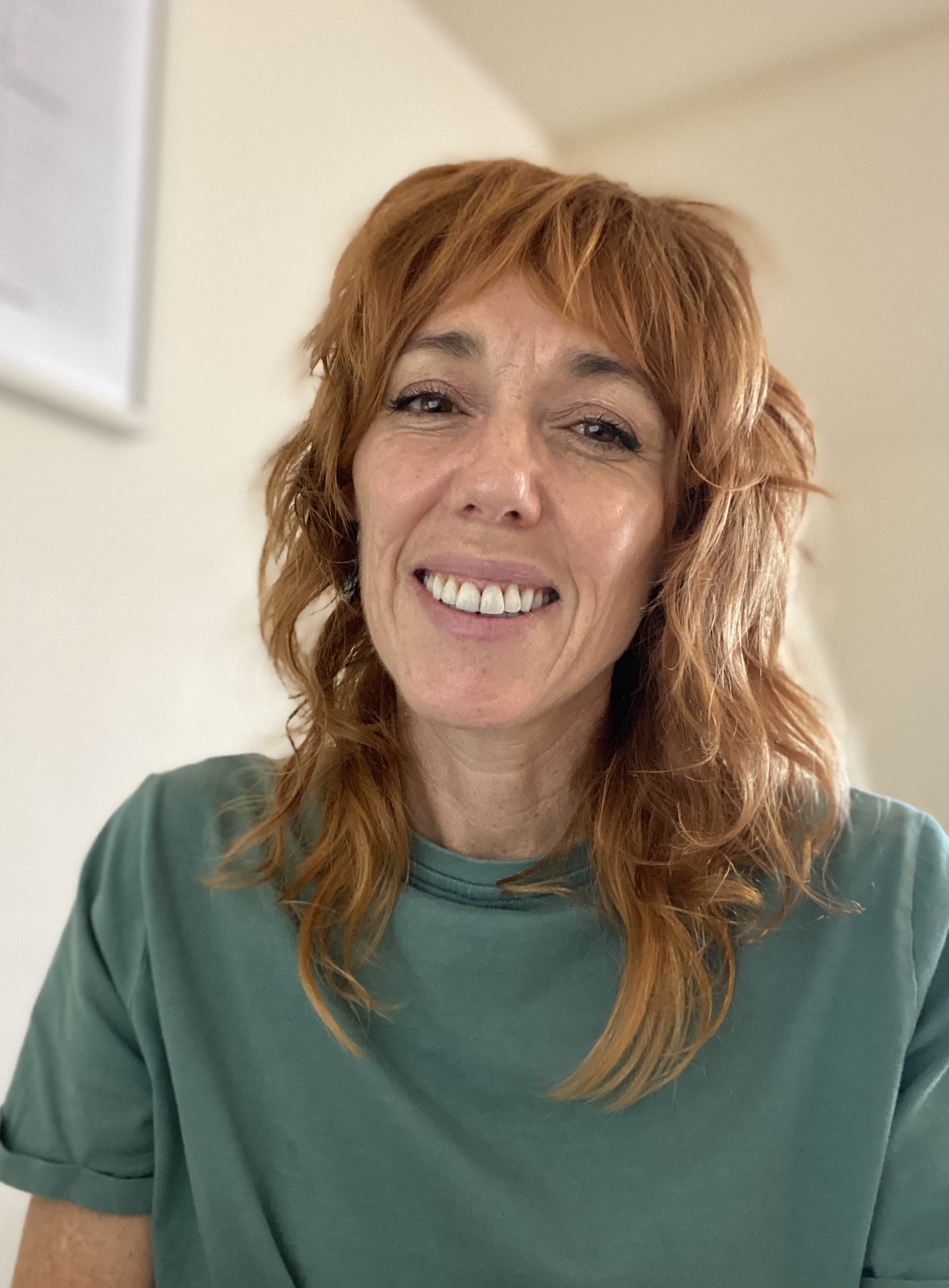 A photo of Julia Hawkins. She is wearing a green t-shirt and smiling at the camera.