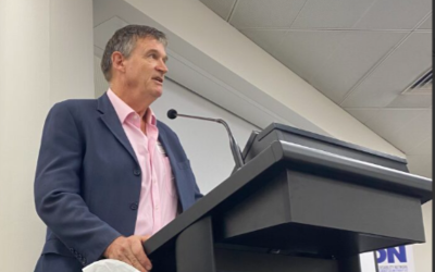 A photo looking up at a man giving a presentation at the roundtable.
