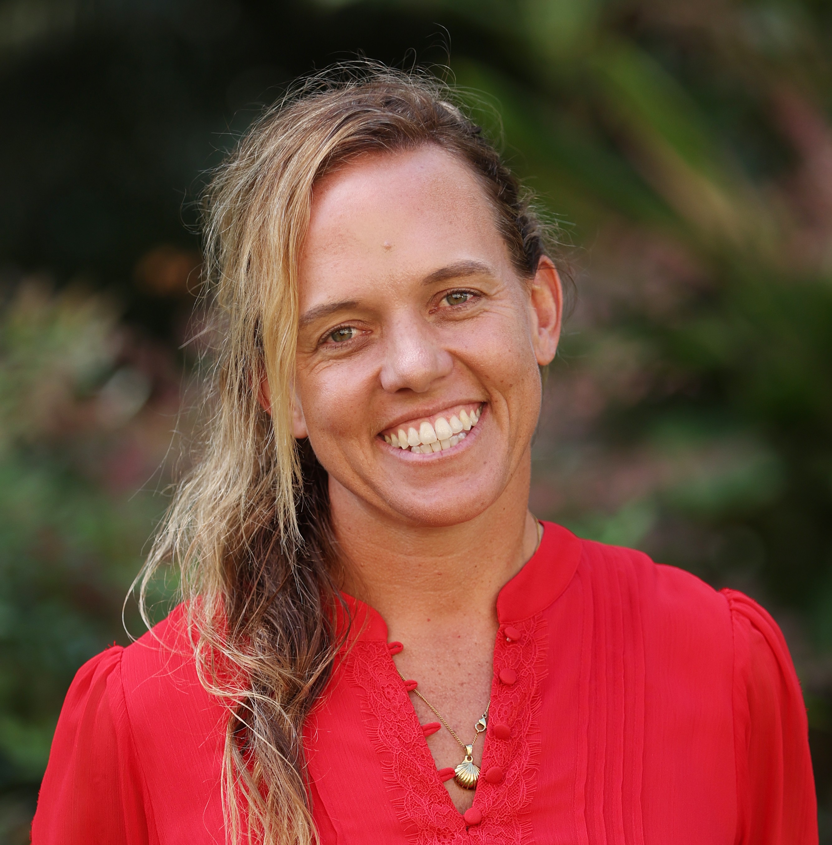 A photo of Kitty-Rose Foley. She is wearing a red shirt and smiling at the camera. She is standing outside.