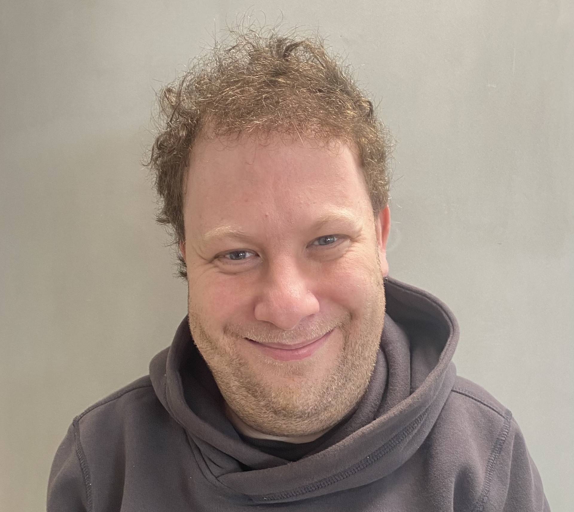 Photo of Michael Sarif. He is wearing a grey top and smiling at the camera.
