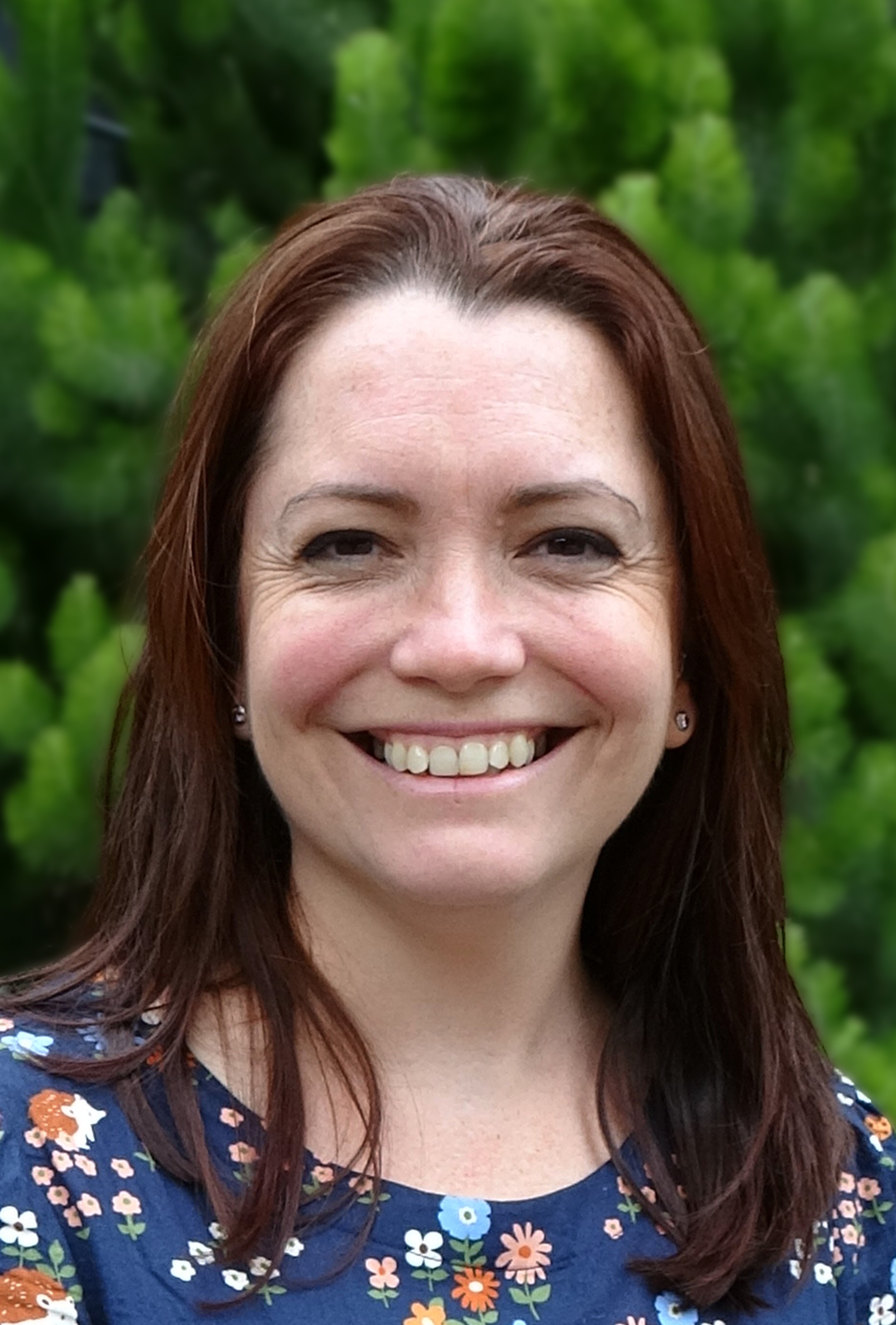 Photo of Rachael Cvejic. She is standing in front of green plants and smiling at the camera.