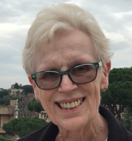 Photo of Helen Leonard. She is wearing a black top and glasses. She is standing outside and smiling at the camera.