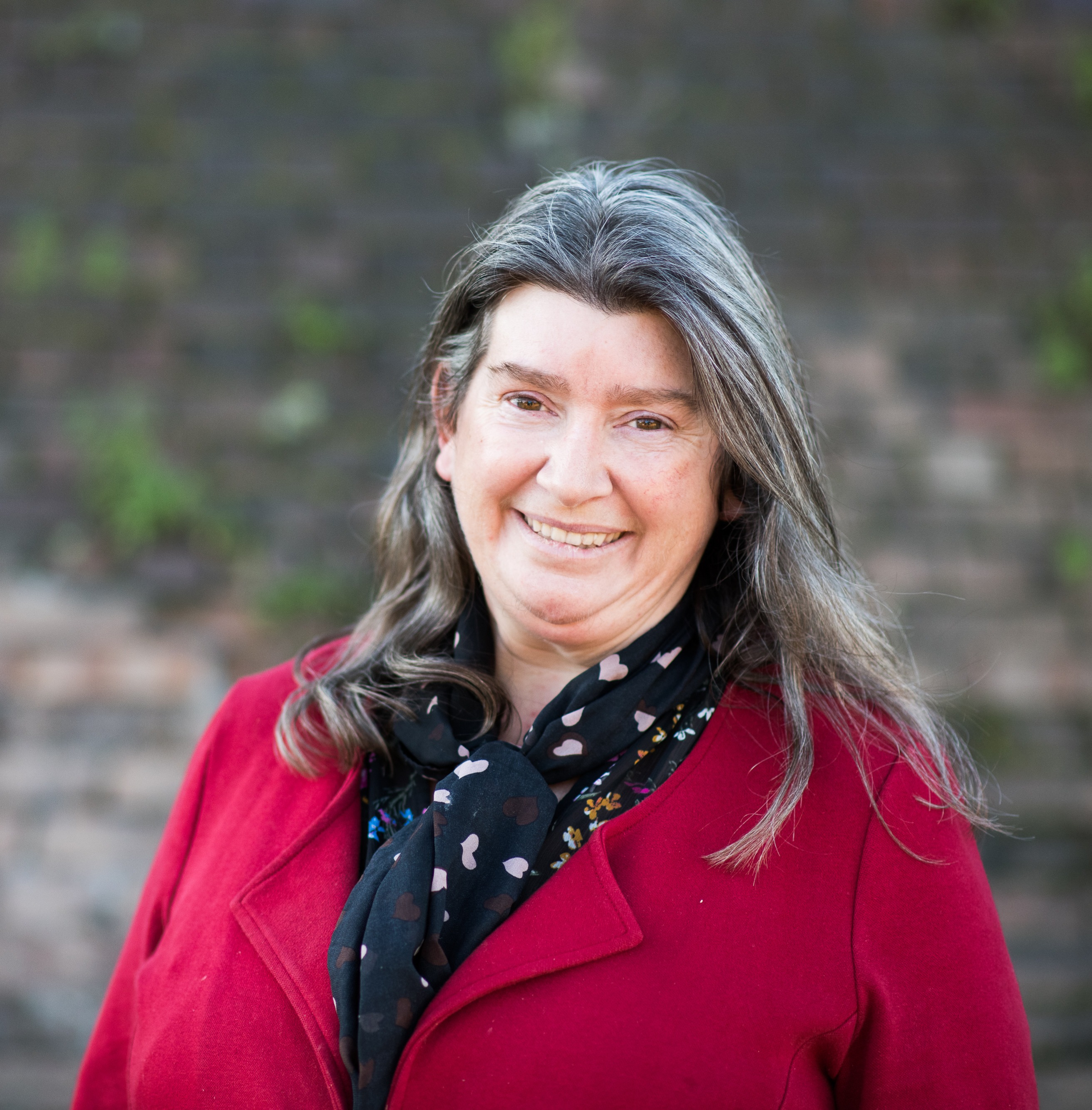 Photo of Raylene Griffiths. She is wearing a red top and smiling at the camera.