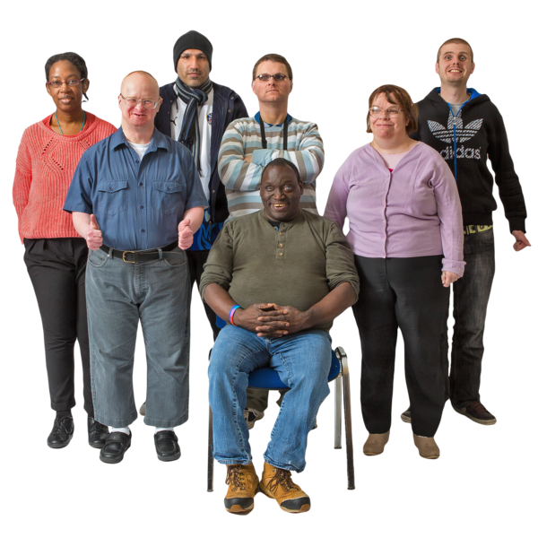 A group of people with intellectual disability. Six are standing. One is sitting on a chair. They are looking at the camera.