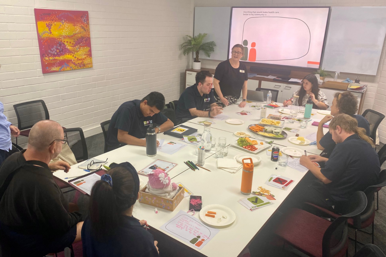 Photo of a group of people sitting around a table writing on worksheets.