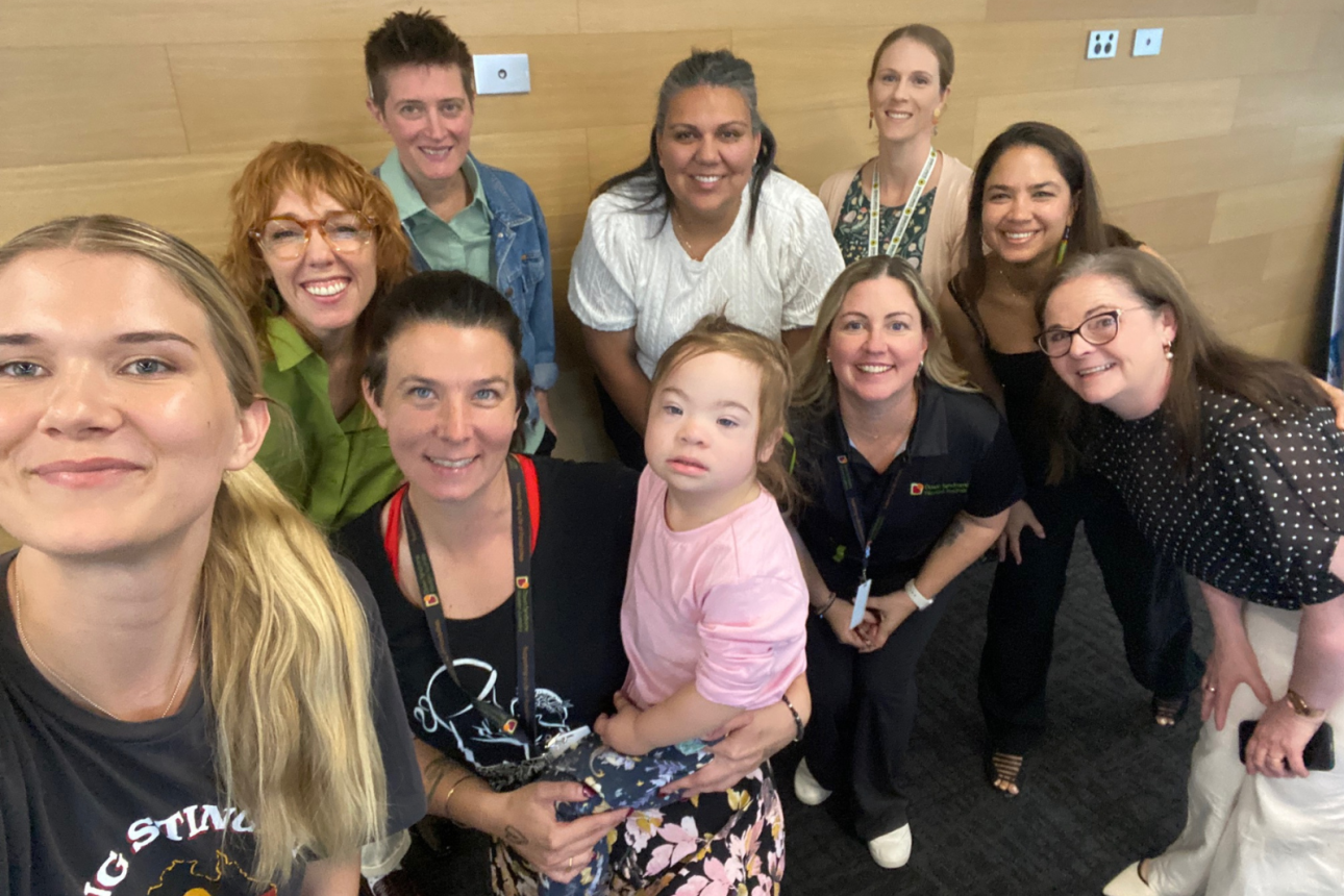 Photo of a group of people looking up at the camera and smiling.