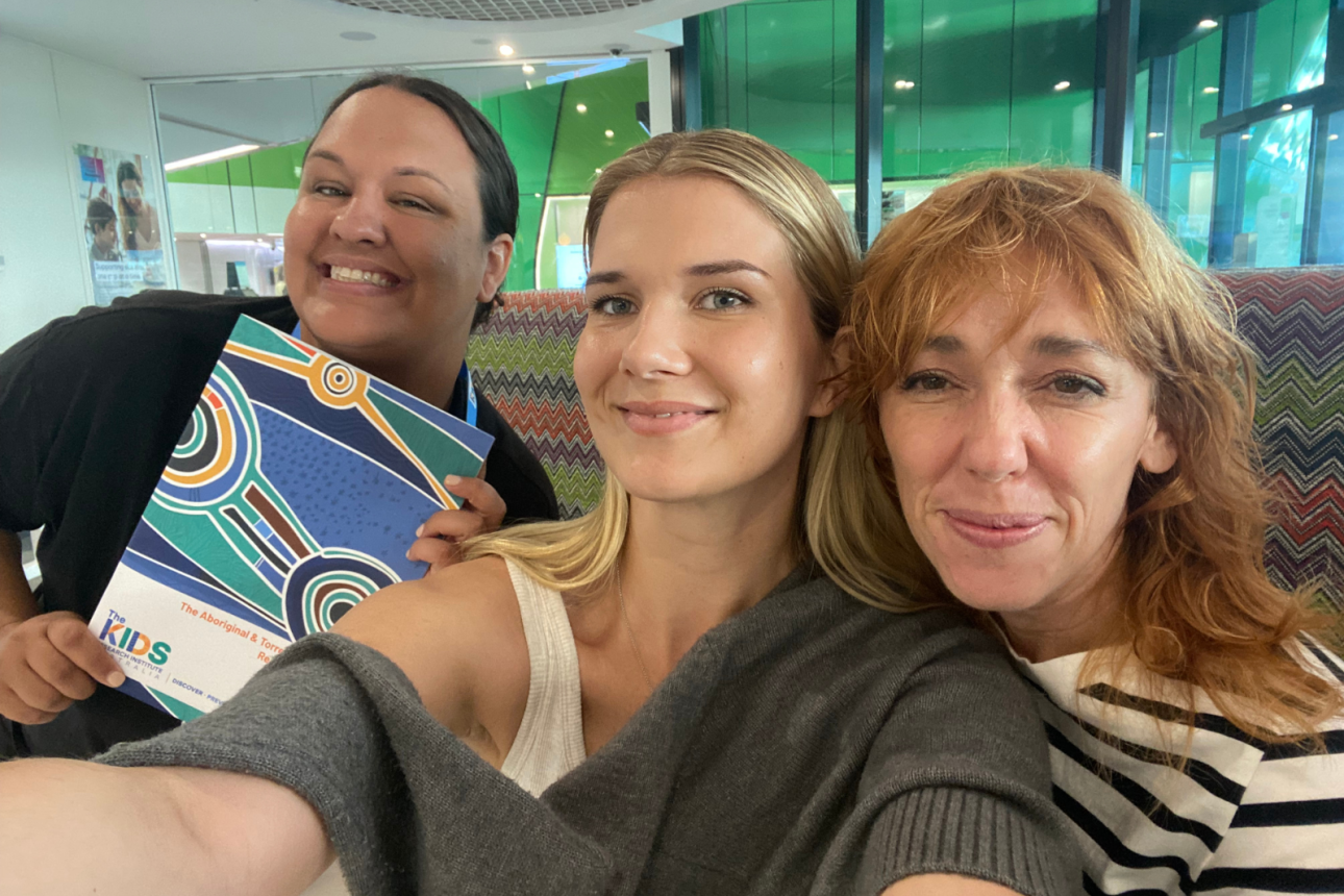 Three people together smiling at the camera. They are standing close together.