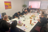 Photo of a group of people sitting around a table writing on worksheets.