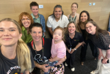Photo of a group of people looking up at the camera and smiling.