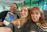 Three people together smiling at the camera. They are standing close together.