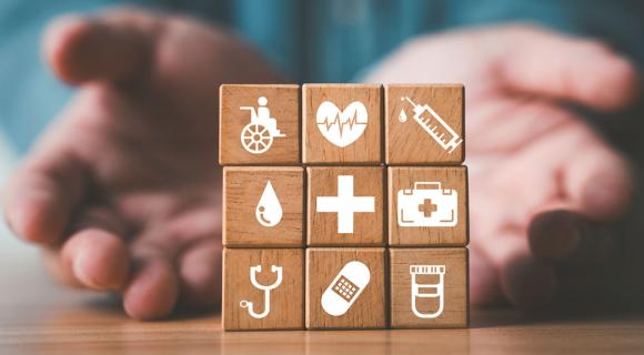 A person builds a square structure out of wooden blocks with different health services