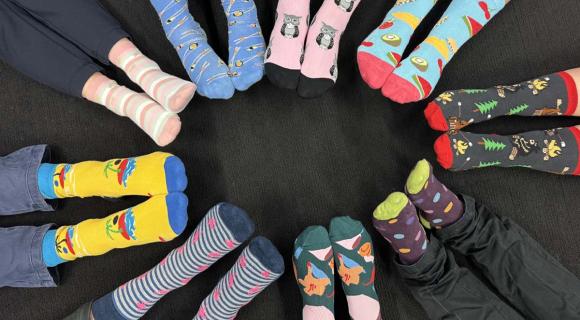 People sitting in a circle with socks of various bright colours representing diversity