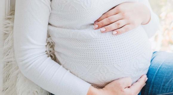 A pregnant person cradles their tummy