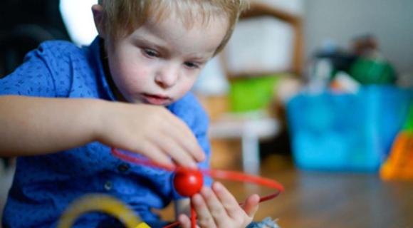 A young boy with intellectual disability plays with toys