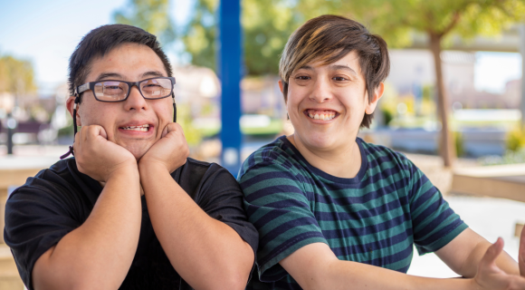 Photo of two young people with intellectual disability sitting together and smiling.