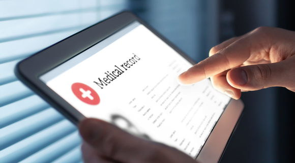 Photo of a digital tablet with Medical Record on the screen. You can see the hands of the person who is holding the tablet.