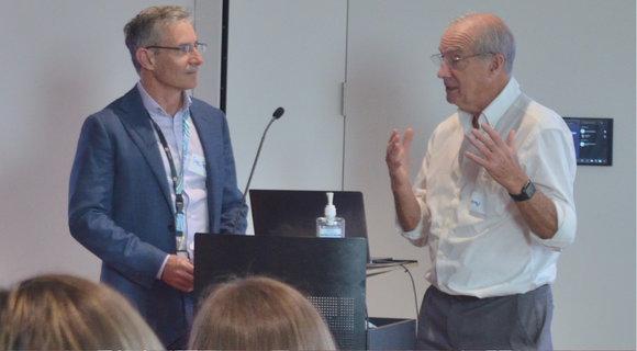 A photo of Professor Julian Trollor and Professor Tony Holland at a presentation. They are in front of an audience talking to each other.