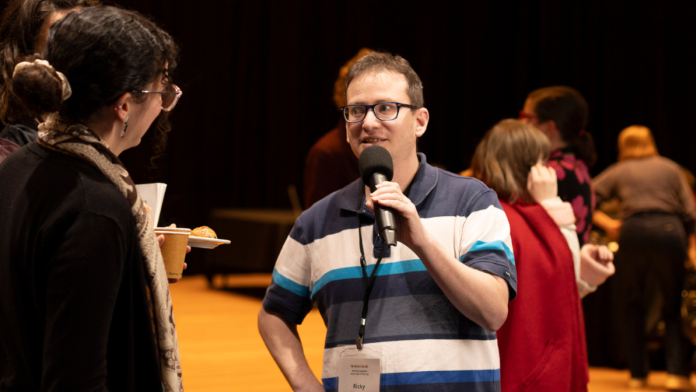 Photo of Ricky Kremer from the Centre holding a microphone and talking to people.