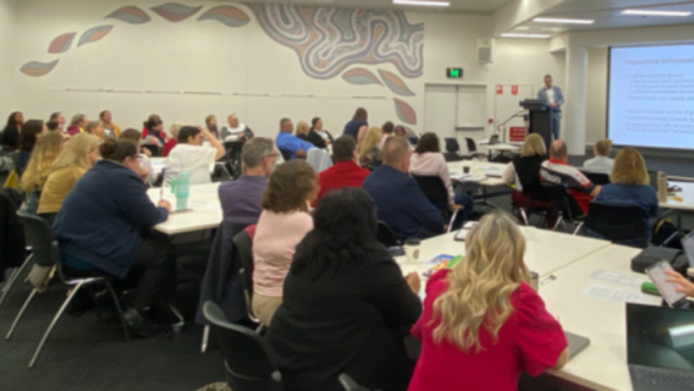 Photo of a group of people at a conference watching a presentation.