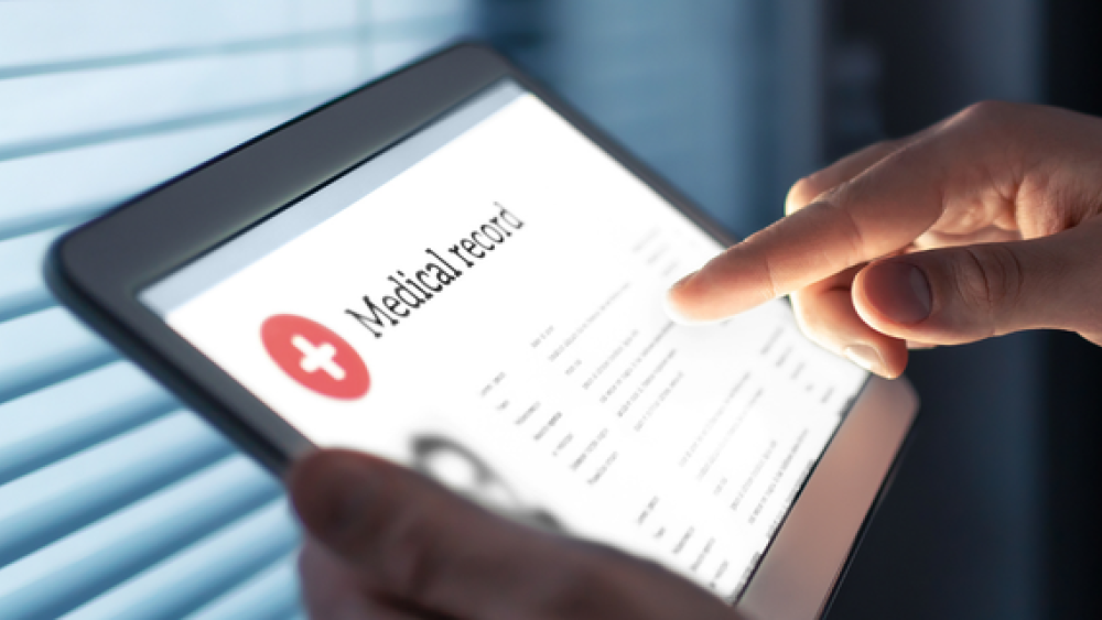 Photo of a digital tablet with Medical Record on the screen. You can see the hands of the person who is holding the tablet.
