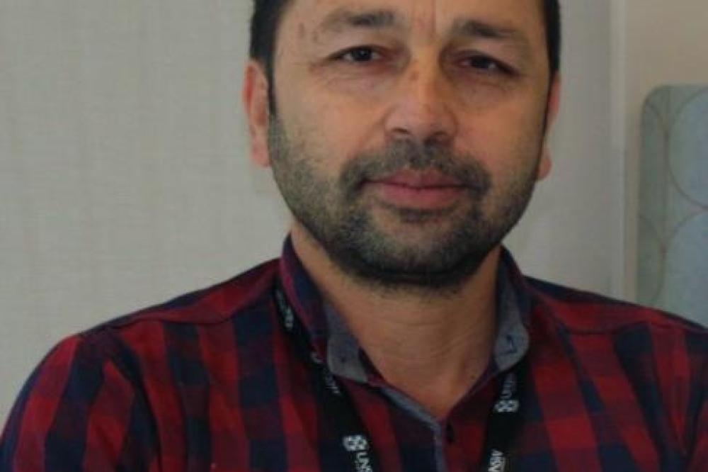 A profile photo of Manzoor Khan. He is wearing a red and blue check shirt.