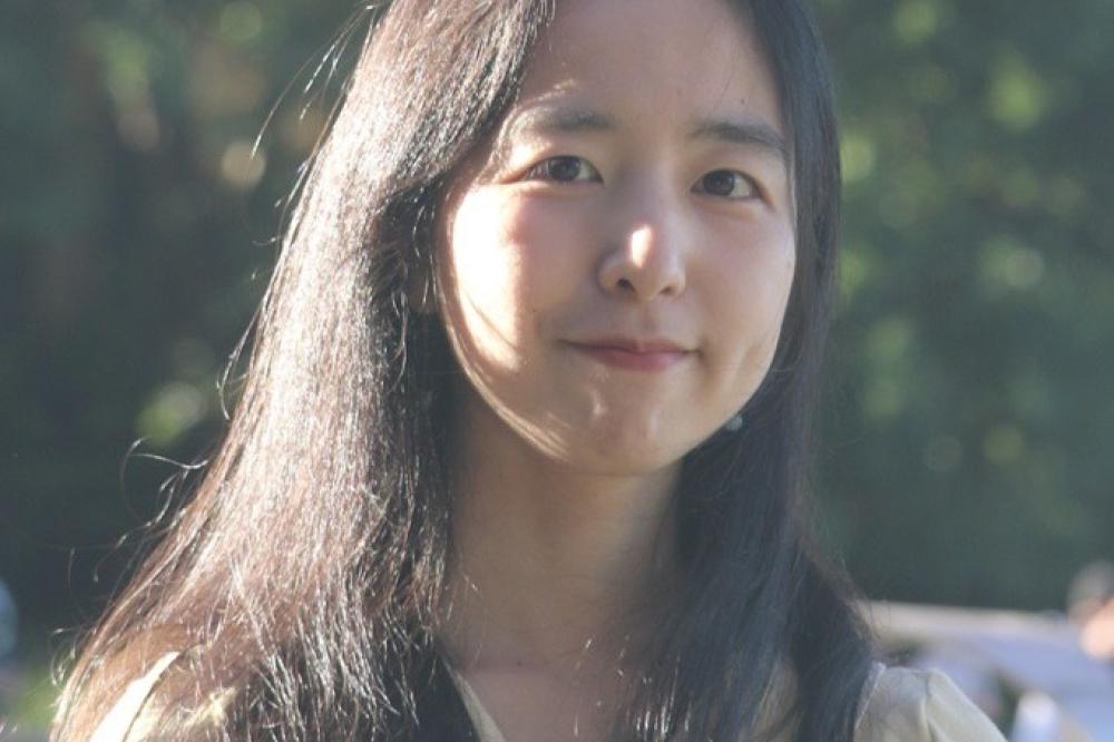 A photo of Peiwen Lao. She is outside. She is looking at the camera and smiling. You can only see her head and shoulders in the photo.