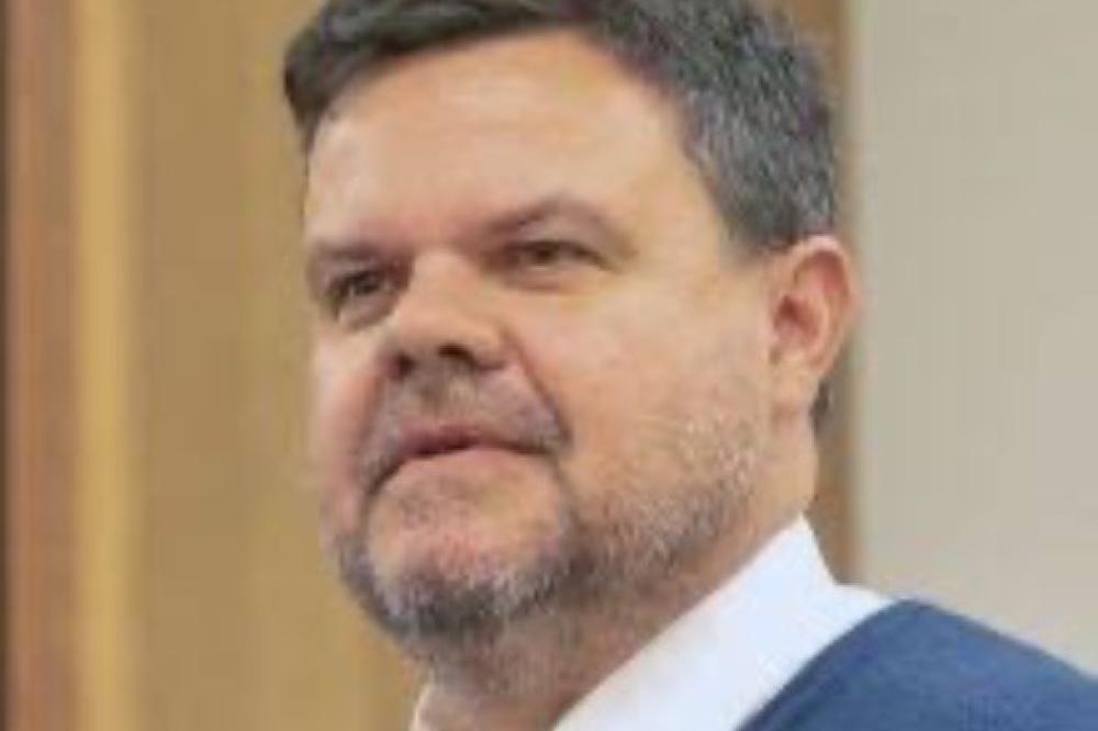 A photo of Damian Griffis. He is wearing a white collar shirt, a red tie, and a blue suit jacket.