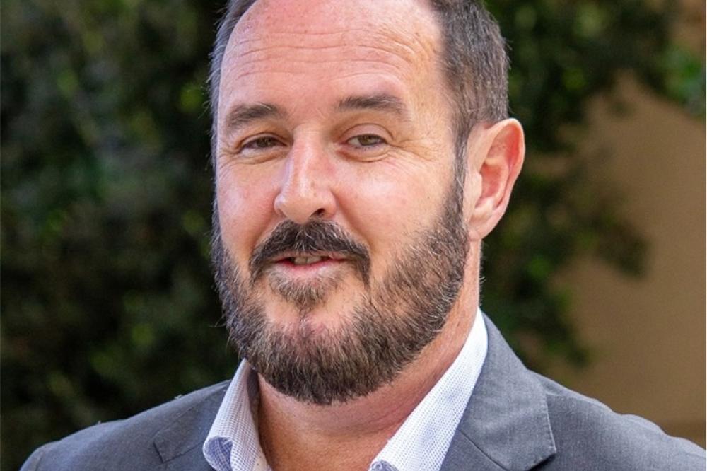 A photo of Heath Dickens. He is wearing a grey suit.