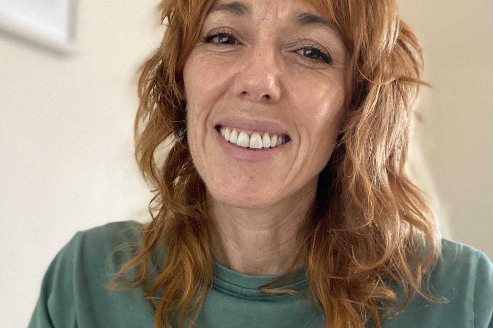 A photo of Julia Hawkins. She is wearing a green t-shirt and smiling at the camera.