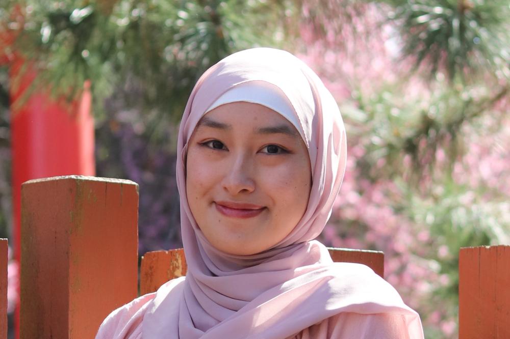 Photo of Aminah Thipayawat. She is wearing pink and smiling at the camera.