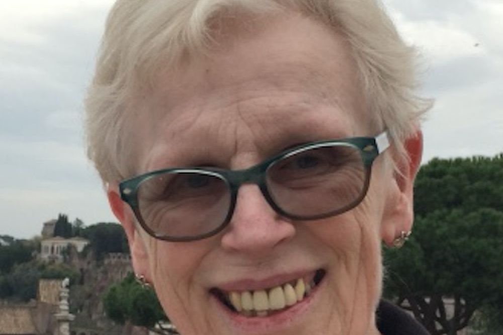 Photo of Helen Leonard. She is wearing a black top and glasses. She is standing outside and smiling at the camera.