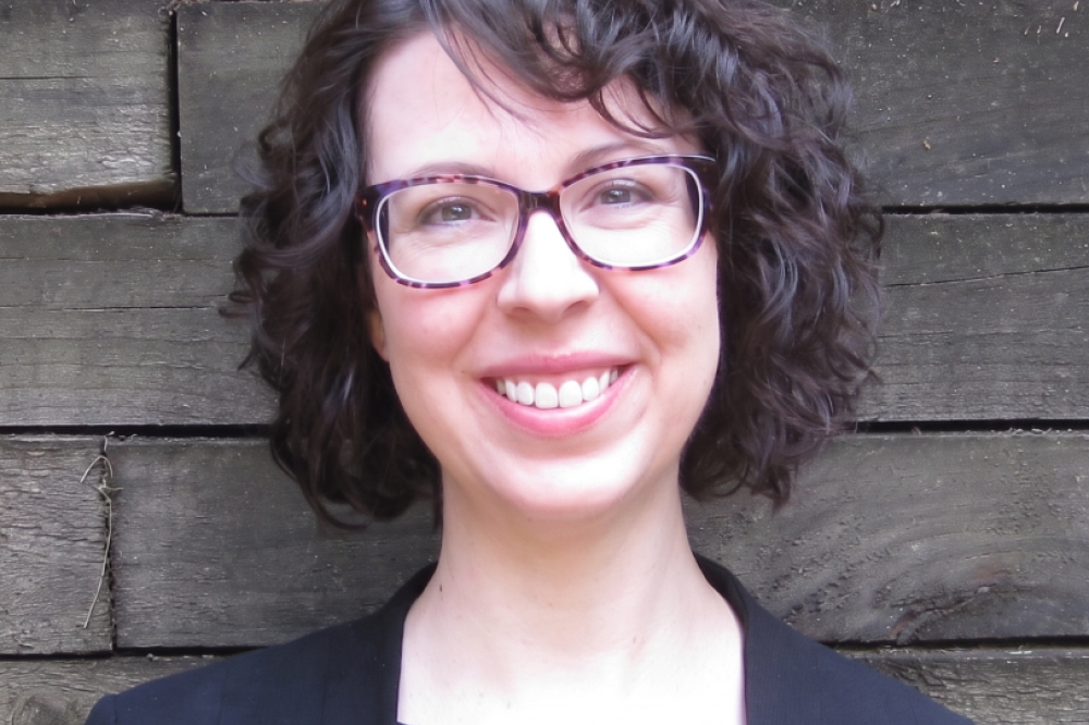 A photo of Liz Convery. She has dark brown curly hair and is smiling at the camera.